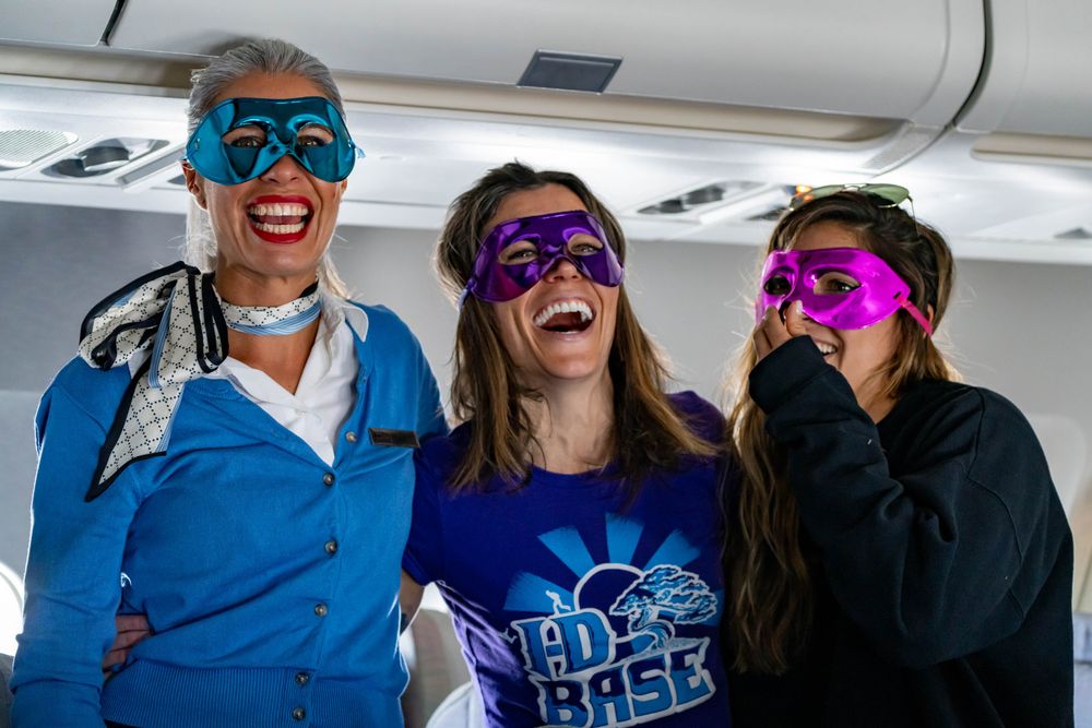 Three women laughing together mid-flight